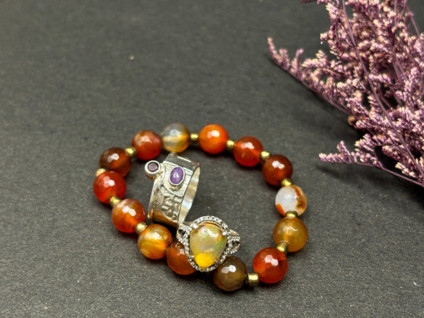 柔和的影棚灯光下，带有复古风格银戒指的红玉髓手链，饰有花卉图案。图片下载