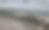 一排笔直的泡沫海浪涌向鹅卵石海滩，远处有船只。图片下载