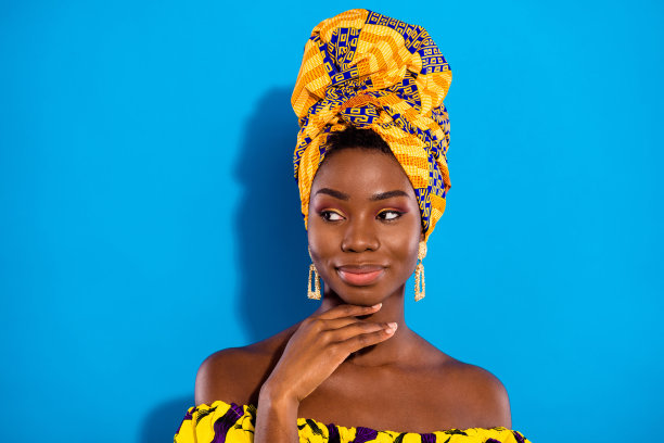 照片：可爱的、积极的、深肤色的人，手臂放在下巴下方，望着空白处，孤立在蓝色背景上图片下载