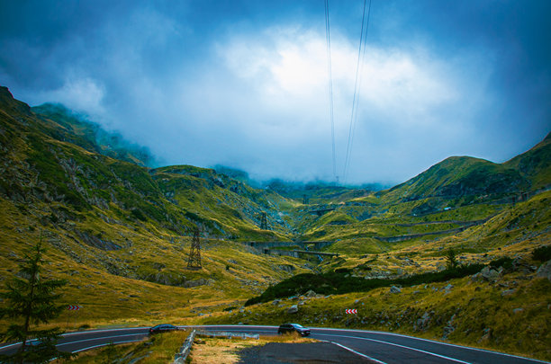 史诗般的蜿蜒山路穿过崎岖的山谷，天空布满戏剧性的云彩图片下载