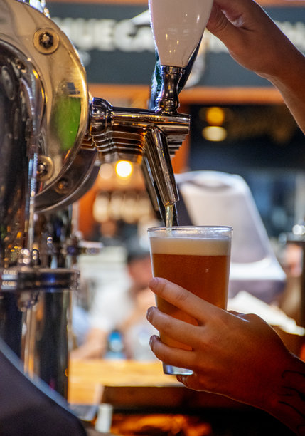 酒吧里有人正在操作啤酒龙头，手握着啤酒龙头手柄。图片下载