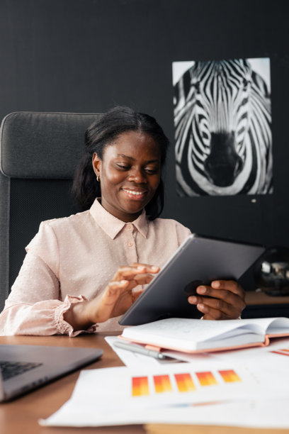 Smiling woman working on tablet in modern office图片下载
