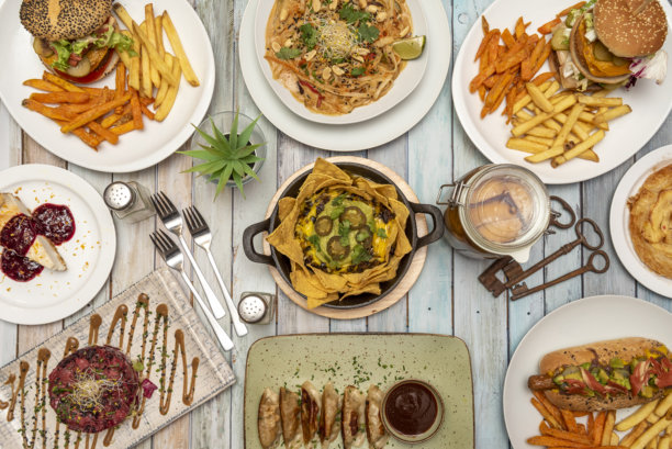 俯视的食物照片。玉米片配鳄梨酱和墨西哥辣椒、煎饺、点心、汉堡配薯条、红金枪鱼塔塔、宽面配坚果、钥匙、叉子、芝士蛋糕图片下载