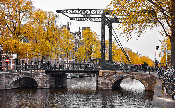 荷兰阿姆斯特丹。秋季荷兰城市的で panoramic 景观。著名的阿姆斯特尔河水道。傍晚的城市景观，有古老的复古金属桥。著名的欧洲旅游目的地，色彩缤纷的日落景象。图片下载