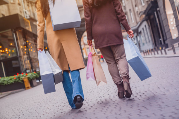 城市购物的女性朋友的特写镜头。女性顾客在购买圣诞节或黑色星期五的衣物礼品时行走的腿部特写照片。折扣与促销。图片下载