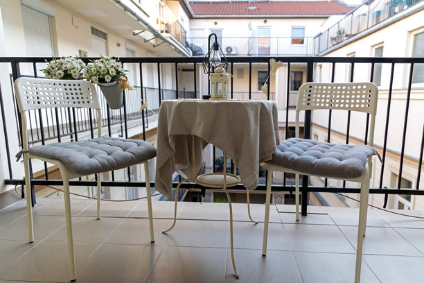 舒适的阳台场景，配有桌子和两把椅子。小阳台场景，特色是圆桌配米色桌布，两把白色椅子配灰色坐垫。图片下载