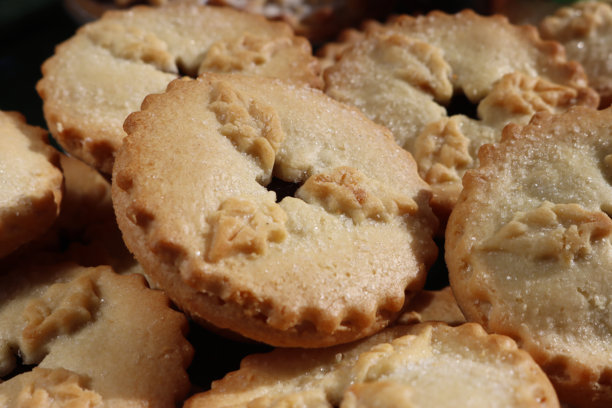 俯视拍摄的圣诞节甜点照片，展示了堆叠的自制肉馅派，酥脆的黄油饼皮包裹着甜美的肉馅，并撒上了糖粉，焦点在前景。图片下载