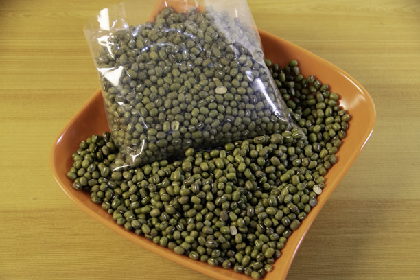 照片，一盘绿豆（Vigna radiata）放在浅棕色的桌子上，在马来语中也被称为“Kacang Hijau”。图片下载