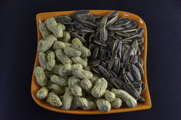 照片，混合咸味花生和瓜子（葵花籽）的俯视照片，装在盘子里，作为零食的概念。图片下载