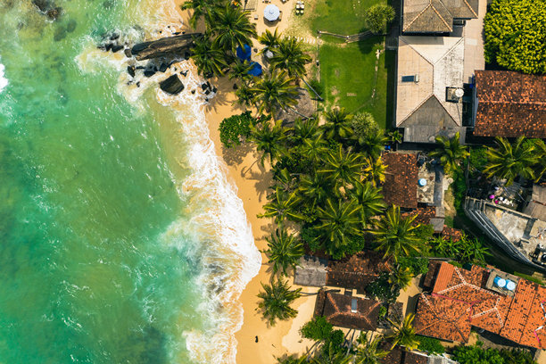 斯里兰卡海滩天堂的航拍照片——蓝色的海洋、茂盛的棕榈树和风景如画的海岸景观图片下载