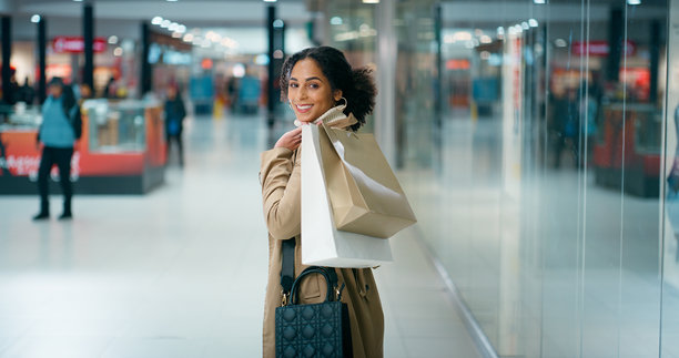 购物或逛街的女人，提着购物袋在商场里，享受零售折扣、黑色星期五促销或 bargain 礼物。开心的顾客，肖像照，购买奢侈品牌，用于精品店推广、服装特卖或优惠活动。图片下载