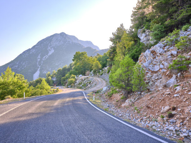 郁郁葱葱的绿色植物和崎岖地形环绕的风景优美的山路图片下载