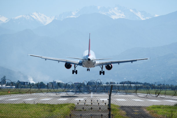 山地机场着陆。飞机在蓝天中飞行，背景是群山。在巴统机场的进近与着陆。图片下载
