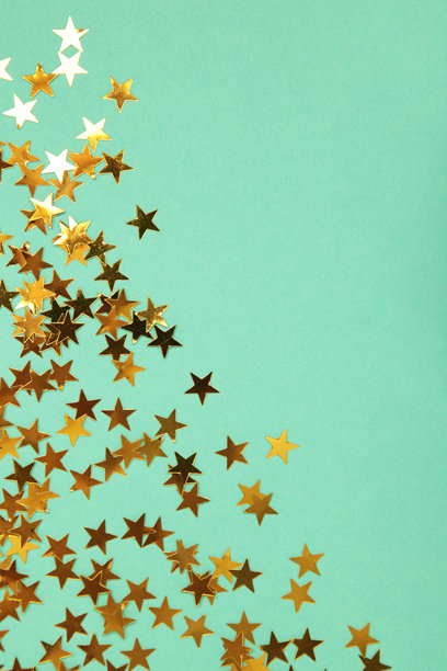 薄荷绿背景上的金色闪光星星。竖幅照片图片下载