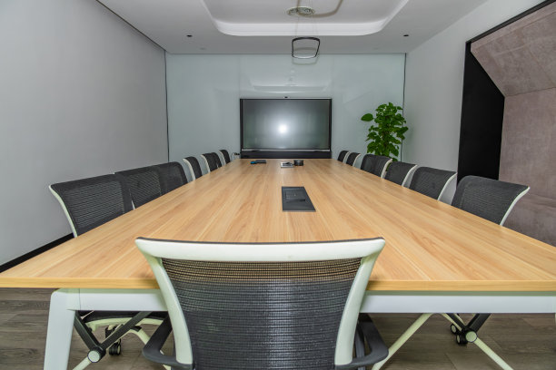 现代会议室内部，长木桌配符合人体工学的椅子，面对大屏幕。图片下载