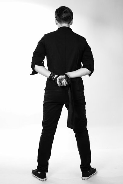 一个衣着时尚的男人，双手被反绑在身后。黑白照片。高质量照片。图片下载