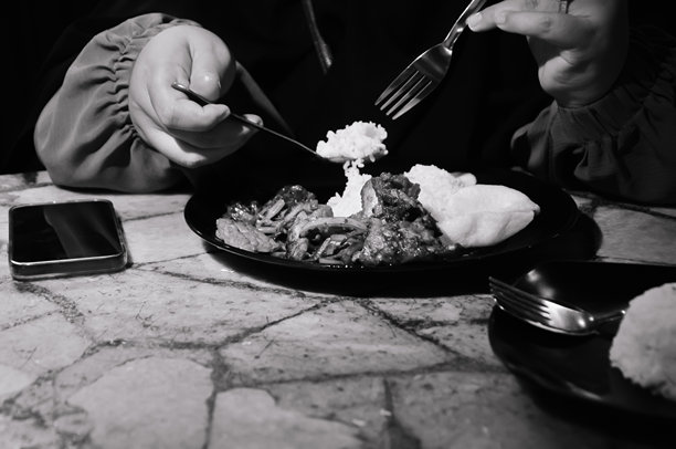 黑白照片，一个人在吃盘子里的食物图片下载