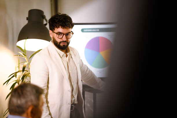 在现代办公室里，一位演示者在会议中讨论商业战略，屏幕上展示着数据，同事们则专心聆听。图片下载