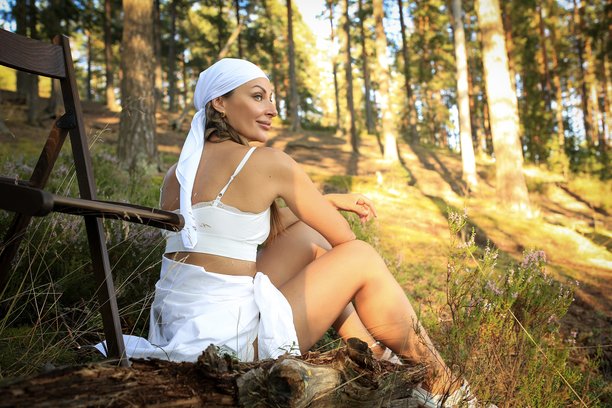 身着白色头巾的女孩在森林背景前与木椅的温柔写照。与自然融为一体。高质量照片。图片下载