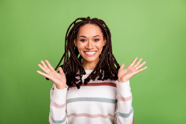 照片，一个快乐的年轻非洲女孩，带着惊喜的表情，在绿色背景前隔离，脸上洋溢着快乐积极的笑容。图片下载