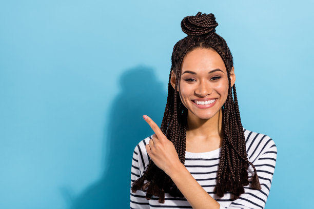 照片：年轻有魅力的黑人女孩，快乐积极的笑容，手指指向空白空间，广告选择，孤立在蓝色背景上图片下载