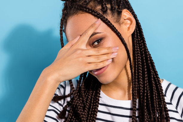 年轻的黑人女孩的特写照片，面带快乐积极的微笑，眼神俏皮，孤立在蓝色背景上图片下载