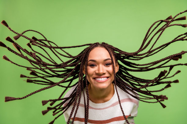 照片：一位快乐、友善的非裔美国年轻女子，头发飞舞，心情愉快，面带微笑，背景为绿色。图片下载