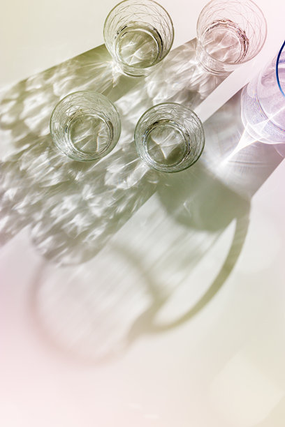 阳光下白色背景上带有阴影的透明玻璃杯和水壶，简约风格的柔和色调照片，自然光下闪闪发光的杯子，夏日饮品，构图。图片下载