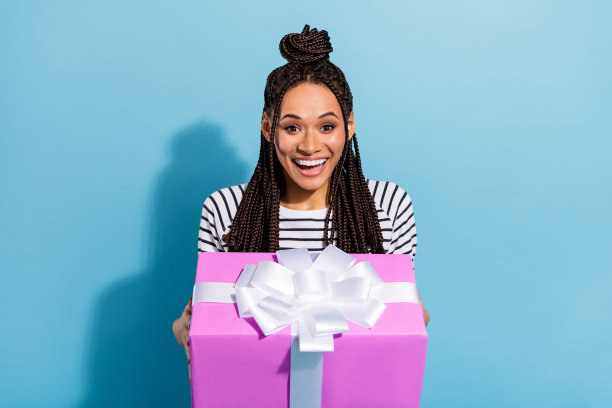 留着脏辫的女孩在生日派对上收到包装好的礼物盒，背景是孤立的粉蓝色，照片肖像图片下载