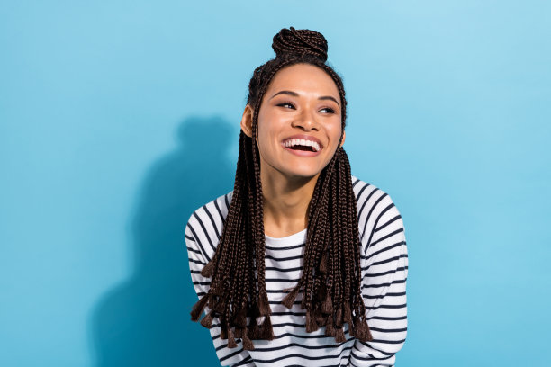 照片肖像：一个留着脏辫的女孩，面带笑容，望着空白处，背景是孤立的粉蓝色。图片下载