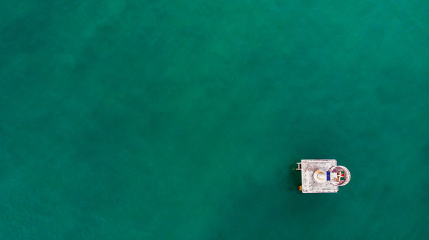 孤零零的海边灯塔，从上方拍摄，四周是无尽的蓝色海水。素材图片图片下载