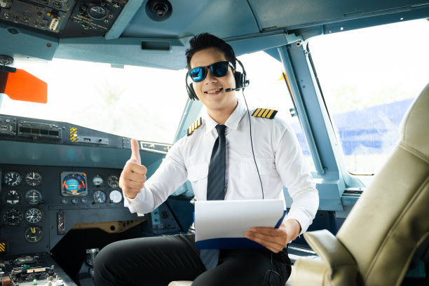 身着制服、戴着耳机的飞行员在飞机驾驶舱内竖起大拇指，非常适合航空、旅行和专业航空生活方式的素材图片图片下载