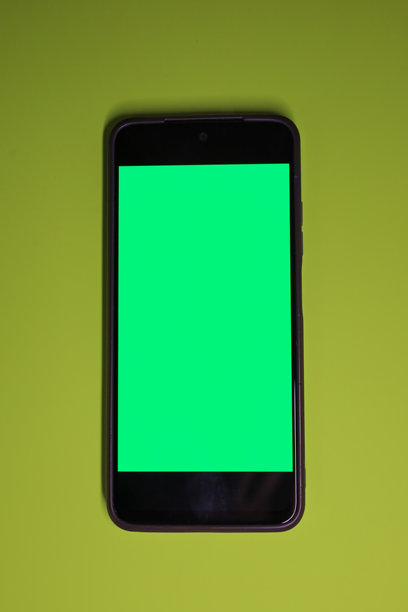 这张垂直的极简风格照片展示了一部智能手机，手机屏幕为亮绿色抠像屏，位于石灰绿或黄绿色背景中央。图片下载