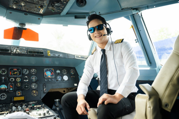 身着制服、戴着耳机的飞行员在飞机驾驶舱内竖起大拇指，非常适合航空、旅行和专业航空生活方式的素材图片图片下载