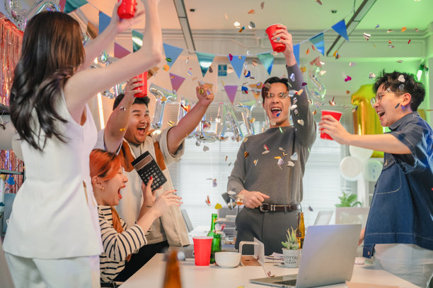 兴奋的办公室团队在夜晚的工作场所庆祝，一起欢呼，为公司惊人的利润增长和胜利成果的公布而激动，并在屏幕上监控财务业绩。图片下载