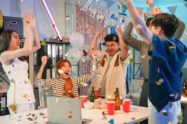 办公室团队兴奋地庆祝盈利增长和胜利成果发布，在工作场所的夜晚庆祝活动中，他们一边在屏幕上监控财务业绩，一边热情地欢呼。图片下载