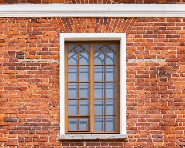 一张特写照片，展示了饱经风霜的红色砖墙外观，上面有一个木框窗户。图片下载