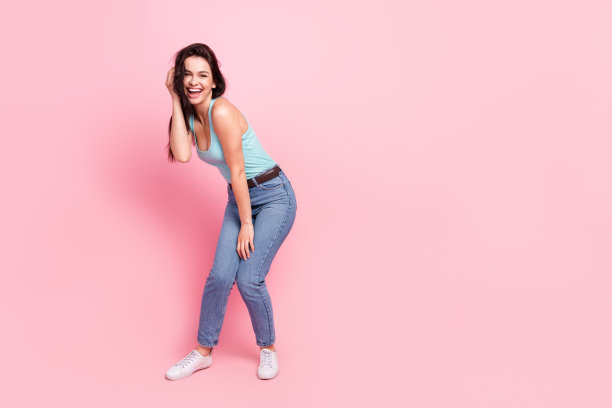 身穿蓝色上衣、牛仔裤和运动鞋的惊讶女士的全身照片，背景为粉色图片下载