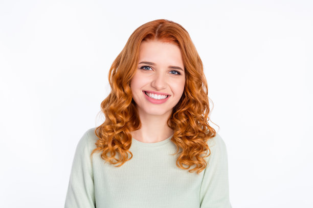 照片：一位有着狐狸般发型、面带微笑、心情愉悦、露出牙齿的可爱年轻女士，孤立在灰色背景上。图片下载