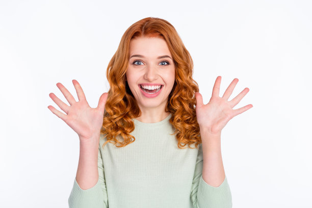 照片：一位快乐、惊讶、惊叹、年轻、友善的女性，双手举起，面带微笑，正在购物，背景为灰色。图片下载