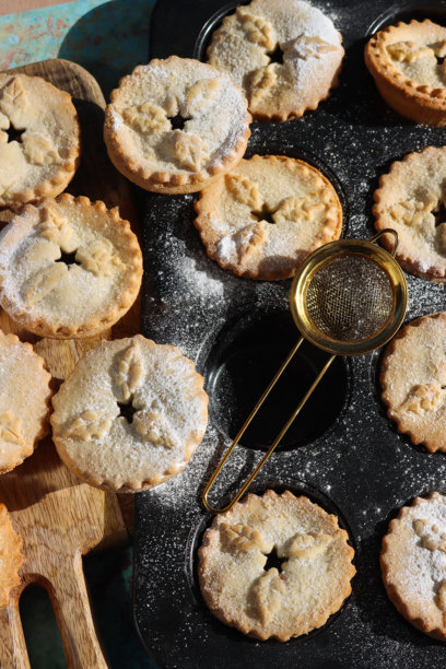 节日氛围的手工面包和肉馅饼，圣诞烘焙场景，包含蛋糕模具、烤盘和糖粉图片下载