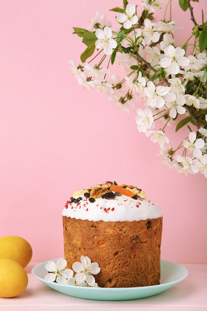 传统复活节蛋糕，撒有彩色糖珠，配有彩蛋、兔子玩偶和春季花卉。竖版照片图片下载