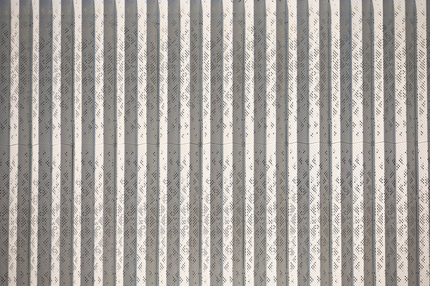 带垂直条纹图案的穿孔金属幕墙。适用于工业、现代或商业建筑设计的建筑纹理。真实照片图片下载