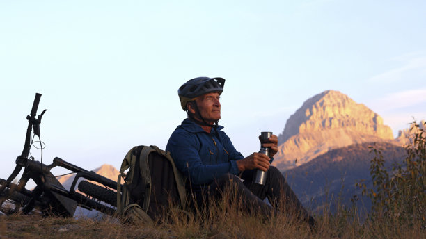 山地车骑手在山间草地上享受饮品图片下载