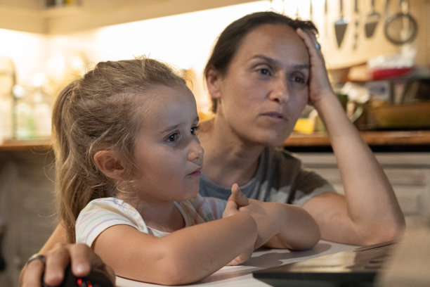 温馨的家庭时光：母亲和孩子深夜在笔记本电脑上看电视图片下载
