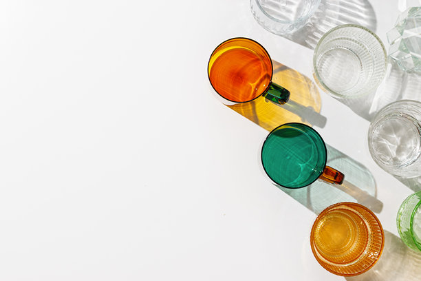 彩色闪亮酒杯静物，白色背景上的阴影和阳光反射，极简美学夏日照片，玻璃杯中的折射和阳光眩光，创意图案图片下载