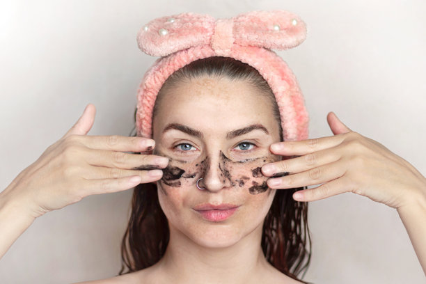 一位白人女性在淋浴后进行黑头泥面膜护理，享受面部皮肤护理，涂抹着黑头泥面膜。该女性有色素沉着、黄褐斑和雀斑。特写肖像照片。图片下载