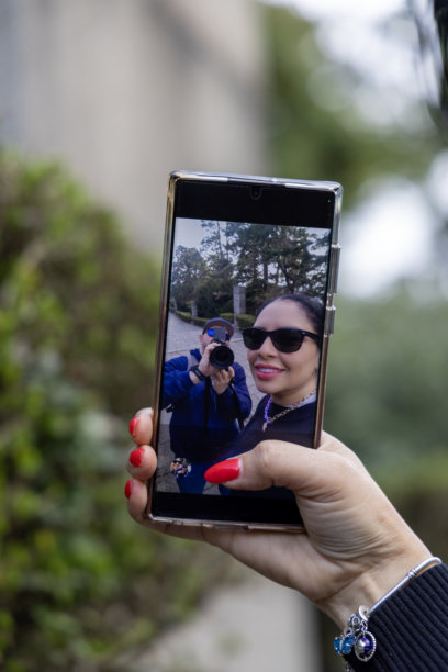 一名女子手持智能手机拍摄自拍照的特写照片图片下载