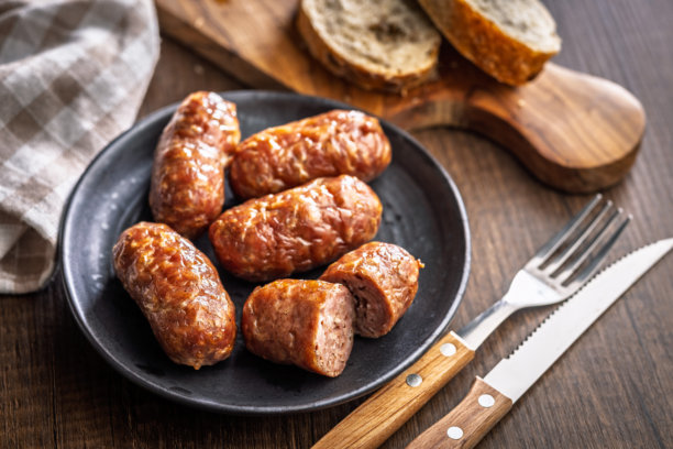 木制餐桌上放着烤意大利香肠Salsiccia的盘子照片。图片下载