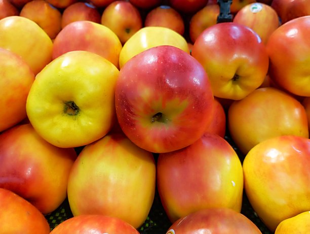 特写照片，展示一个箱子里摆放的红苹果和黄苹果。苹果表皮纹理的特写。在市场和超市销售的水果图片下载